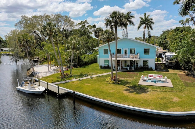 back of property featuring a patio, a balcony, a lawn, and a water view