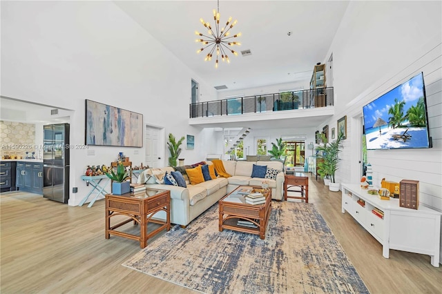 living room featuring a notable chandelier, a towering ceiling, and light hardwood / wood-style floors