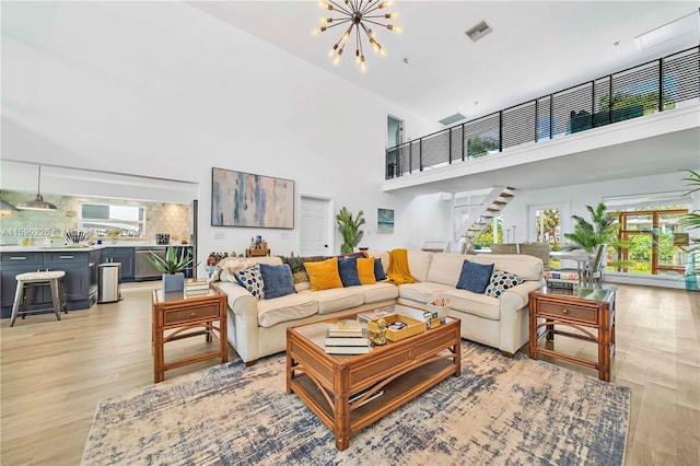 living room featuring a healthy amount of sunlight, a towering ceiling, light wood-type flooring, and a chandelier