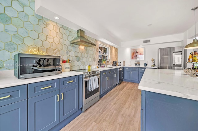 kitchen featuring light hardwood / wood-style floors, appliances with stainless steel finishes, blue cabinetry, wall chimney exhaust hood, and backsplash