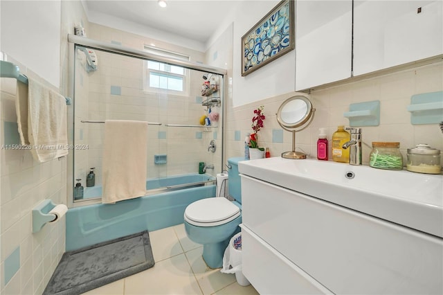 full bathroom featuring tile walls, shower / bath combination with glass door, tile floors, toilet, and large vanity