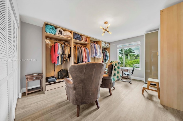 spacious closet with a notable chandelier and light hardwood / wood-style floors