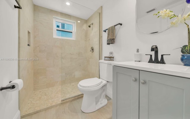 bathroom with a tile shower, vanity, and toilet