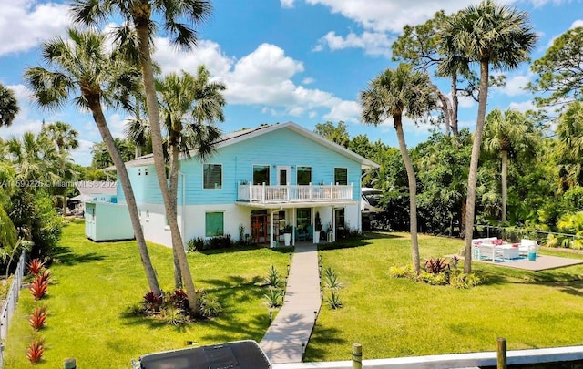 rear view of house with a swimming pool, a lawn, and a balcony