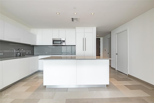 kitchen with white cabinets, a center island, sink, and tasteful backsplash