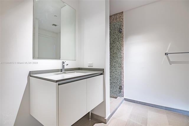 bathroom with tile flooring, tiled shower, and vanity