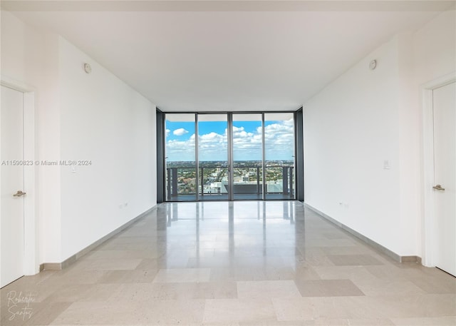 spare room featuring light tile flooring and a wall of windows