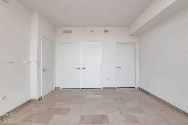 unfurnished bedroom with a closet and light tile floors