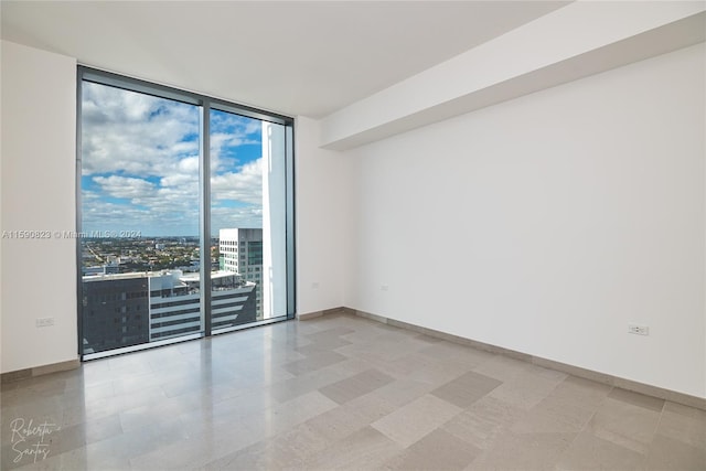 unfurnished room with a healthy amount of sunlight, tile flooring, and a wall of windows