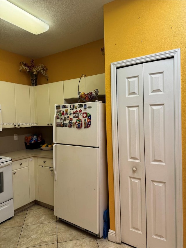 kitchen featuring light tile patterned flooring, a textured ceiling, and white appliances