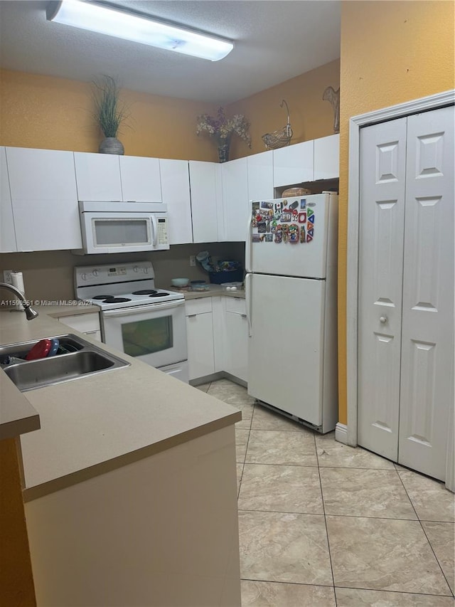 kitchen with sink, white cabinetry, white appliances, and light tile patterned floors