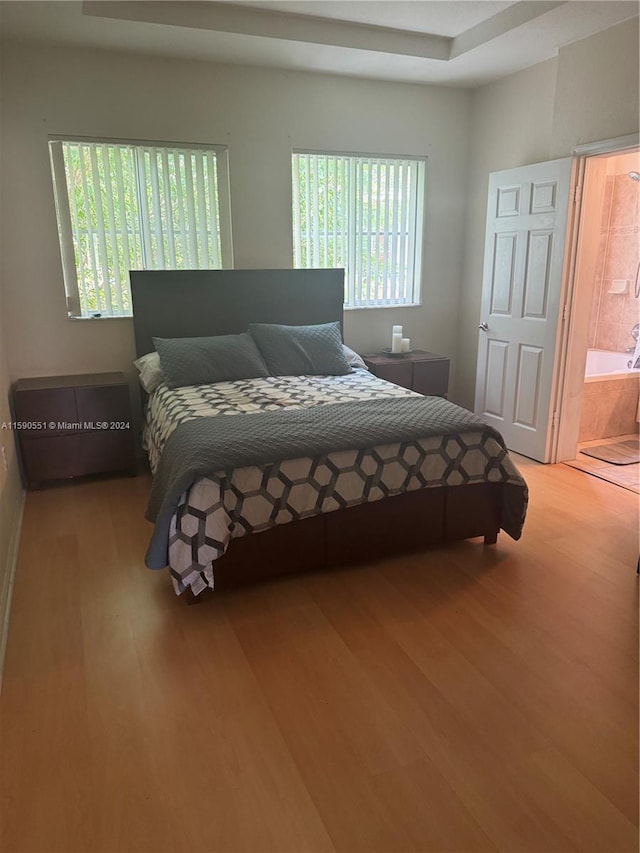 bedroom with connected bathroom and hardwood / wood-style flooring