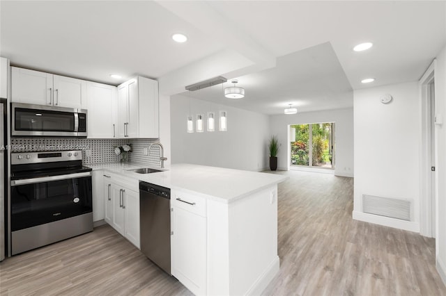 kitchen featuring light hardwood / wood-style floors, kitchen peninsula, tasteful backsplash, stainless steel appliances, and sink