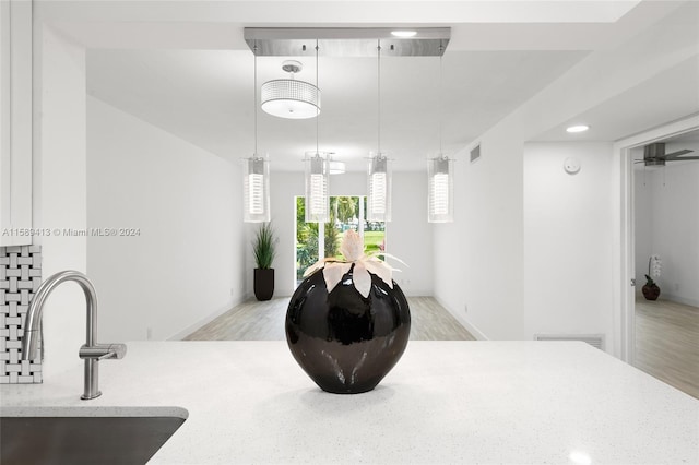 interior space featuring light hardwood / wood-style flooring, light stone counters, decorative light fixtures, sink, and ceiling fan