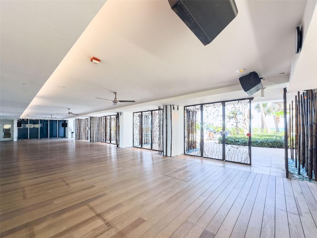 interior space featuring expansive windows, ceiling fan, and light wood-type flooring