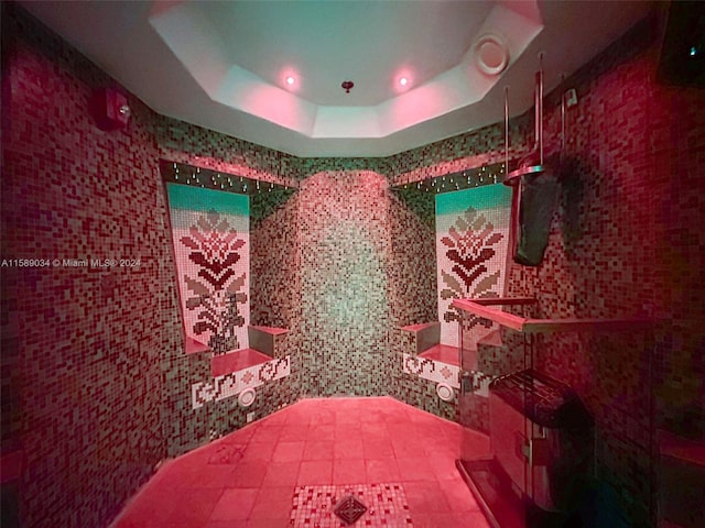 bathroom featuring a tray ceiling and tile walls