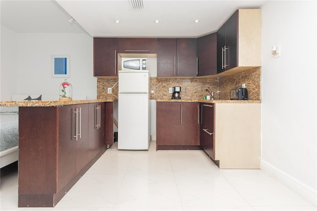 kitchen featuring kitchen peninsula, white appliances, light tile flooring, and tasteful backsplash