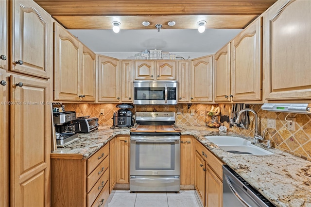 kitchen featuring stainless steel appliances, backsplash, sink, and light tile floors