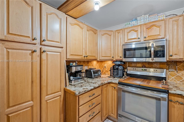 kitchen with light stone counters, stove, tasteful backsplash, and light brown cabinetry