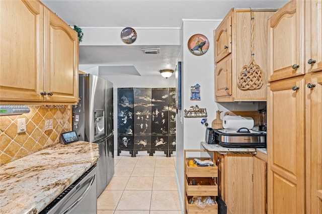 kitchen with appliances with stainless steel finishes, light stone counters, backsplash, light tile flooring, and light brown cabinetry