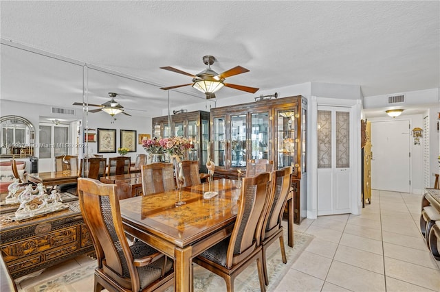 dining space featuring light tile flooring, ceiling fan, and a textured ceiling