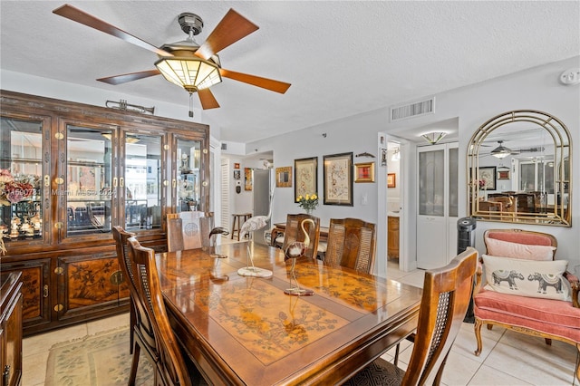 dining space with ceiling fan, a textured ceiling, and light tile floors