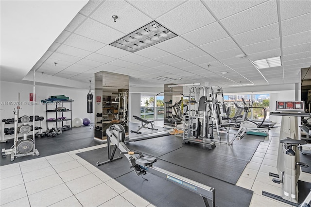 exercise room with tile flooring, a wealth of natural light, and a paneled ceiling