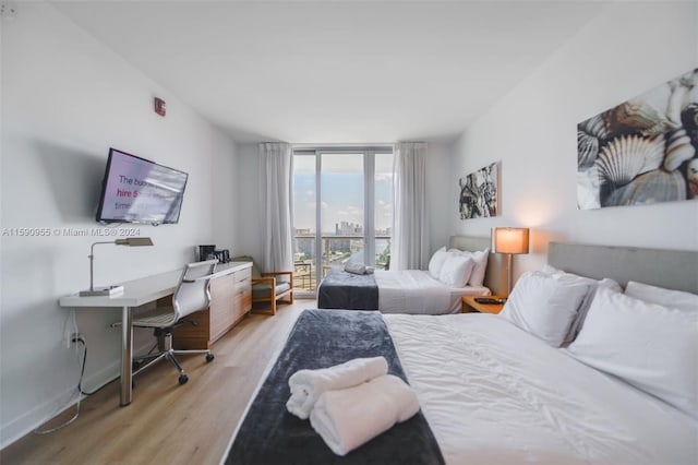 bedroom featuring expansive windows and light hardwood / wood-style floors