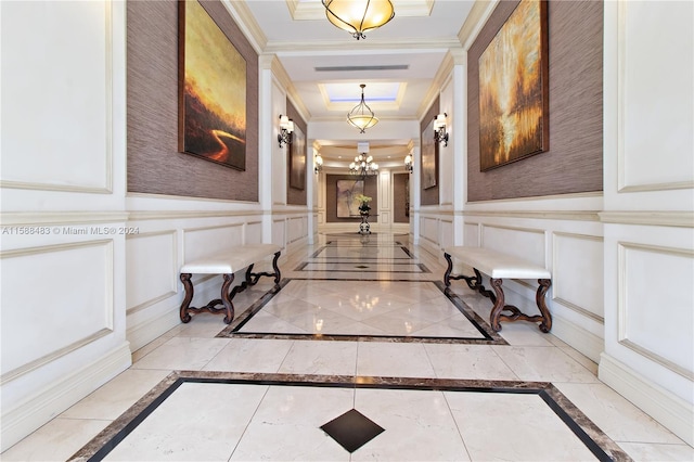 hallway featuring a tray ceiling, crown molding, a chandelier, and light tile floors