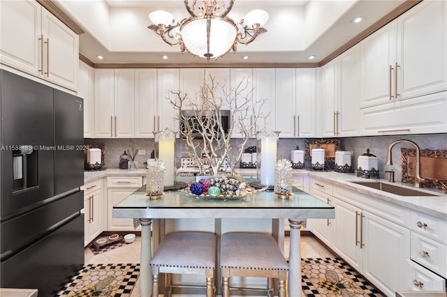 kitchen featuring black fridge, a raised ceiling, backsplash, and sink