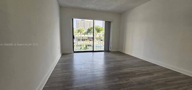 empty room with dark hardwood / wood-style flooring and a textured ceiling