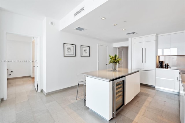 kitchen with a center island, beverage cooler, a breakfast bar area, and white cabinetry