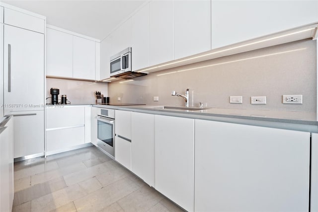 kitchen with stainless steel appliances, white cabinets, and sink