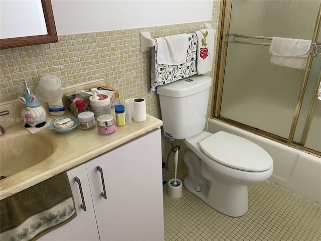 full bathroom with tile flooring, tile walls, enclosed tub / shower combo, vanity, and toilet