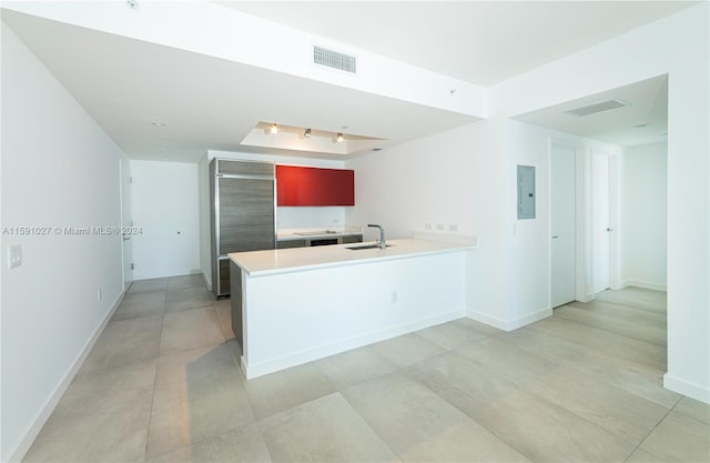 kitchen featuring light tile patterned floors, electric panel, sink, and kitchen peninsula