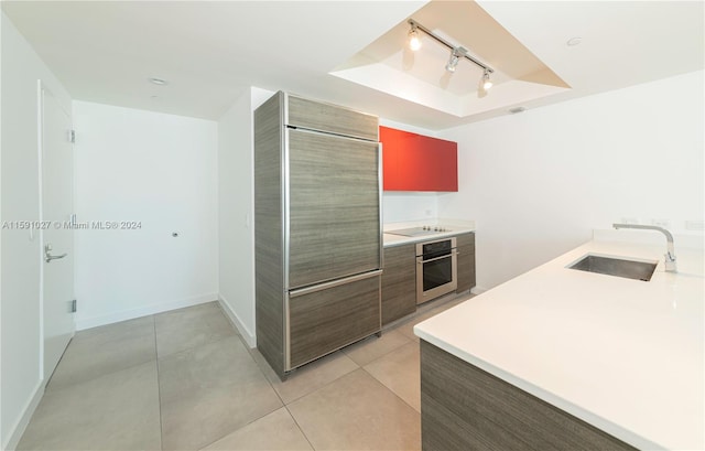 kitchen with oven, light tile patterned floors, rail lighting, and sink