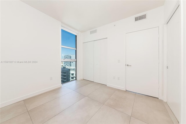 unfurnished bedroom featuring light tile patterned floors and expansive windows