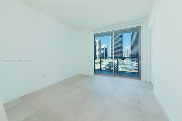 spare room featuring a wall of windows and light tile patterned flooring