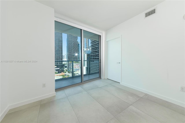 empty room with light tile patterned flooring and expansive windows