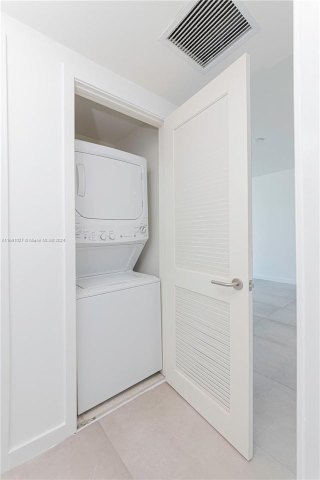 laundry room with stacked washer and dryer and light tile patterned floors