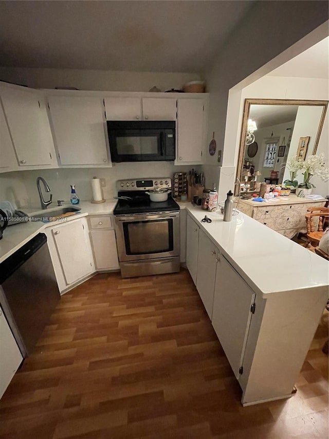 kitchen with appliances with stainless steel finishes, kitchen peninsula, white cabinetry, and dark hardwood / wood-style flooring