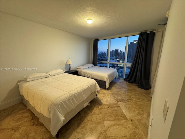 tiled bedroom featuring a textured ceiling and a wall of windows