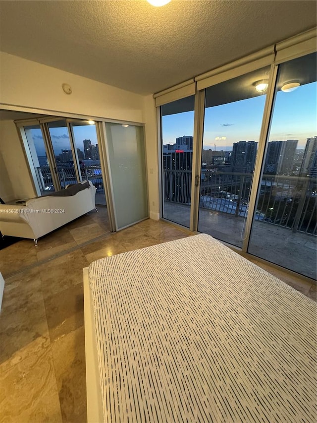 unfurnished bedroom with floor to ceiling windows, a textured ceiling, and access to outside