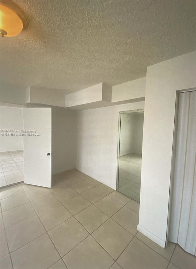 unfurnished room featuring light tile patterned floors and a textured ceiling