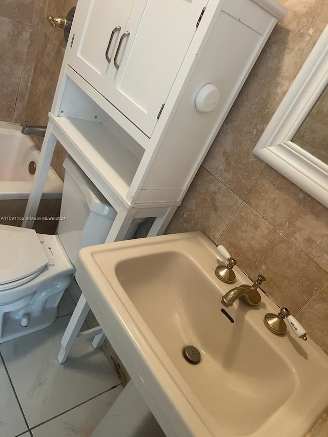 bathroom with sink, tile patterned flooring, a bath, and toilet