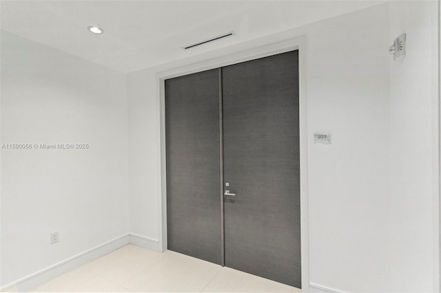 unfurnished bedroom featuring baseboards, recessed lighting, tile patterned floors, and a closet