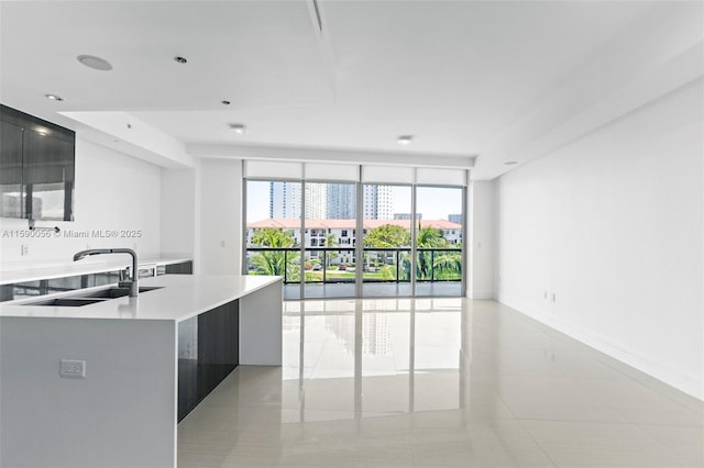 kitchen featuring open floor plan, light tile patterned flooring, light countertops, and a sink