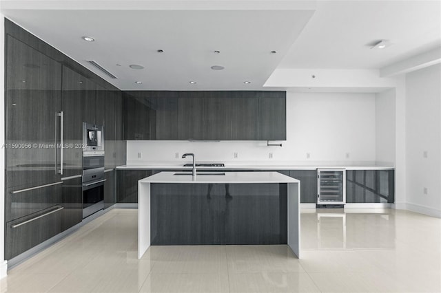 kitchen with a center island with sink, sink, beverage cooler, and light tile floors