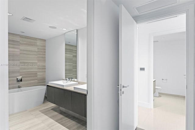 bathroom with a soaking tub, visible vents, toilet, recessed lighting, and vanity