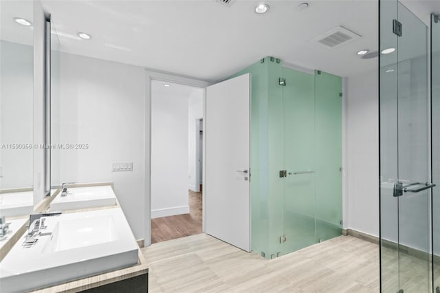 full bath with wood finished floors, a shower stall, visible vents, and a sink